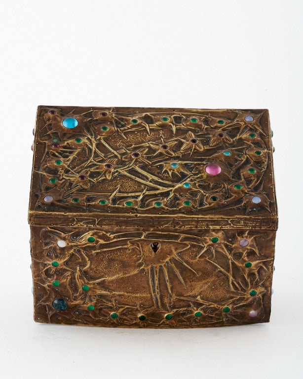 In this magical brass over wood box with Glass cabochons ambiguity of subject prevails, where repoussé metalwork and cabochons simultaneously suggest comets, starbursts, exoskeletal insects, and thorny plants. The combination of materials and