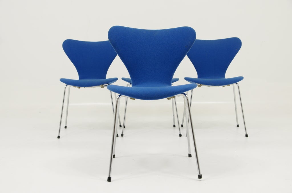 Set of four Series 7 stacking chairs designed by Arne Jacobsen for Fritz Hansen. Model #3107.Original blue fabric needs to be recovered. Frames are structurally sound with one original rubber foot missing. Labeled underneath the seat with the Fritz