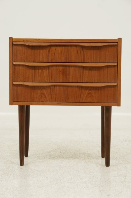 Great little bedside table or night stand in teak. Three drawers add to the function of this sharp little piece. Nicely sculpted drawer pulls are integrated in the design. Condition is overall great and finish is original. Shipping will be $70 by
