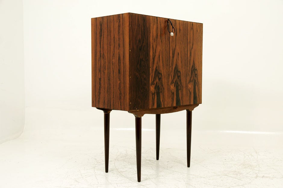 Gorgeous little rosewood cocktail cabinet or bar cabinet designed by Illum Wikkelso. This cabinet has two small doors that open to a mirrored interior and a single textured shelf. Small bottle holders are on the inside of each door. Small little