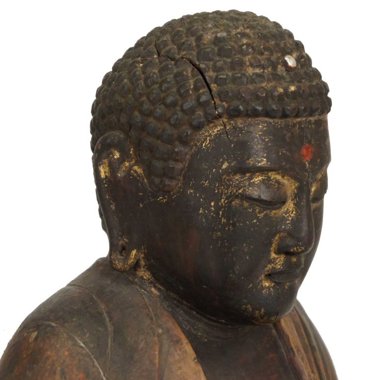 A tranquil Buddha figure seated cross-legged with the hands arranged in a meditation mudra with the right hand pointing upward and the left downward; each with the thumb and index finger forming a circle. This early figure is finely carved from pine