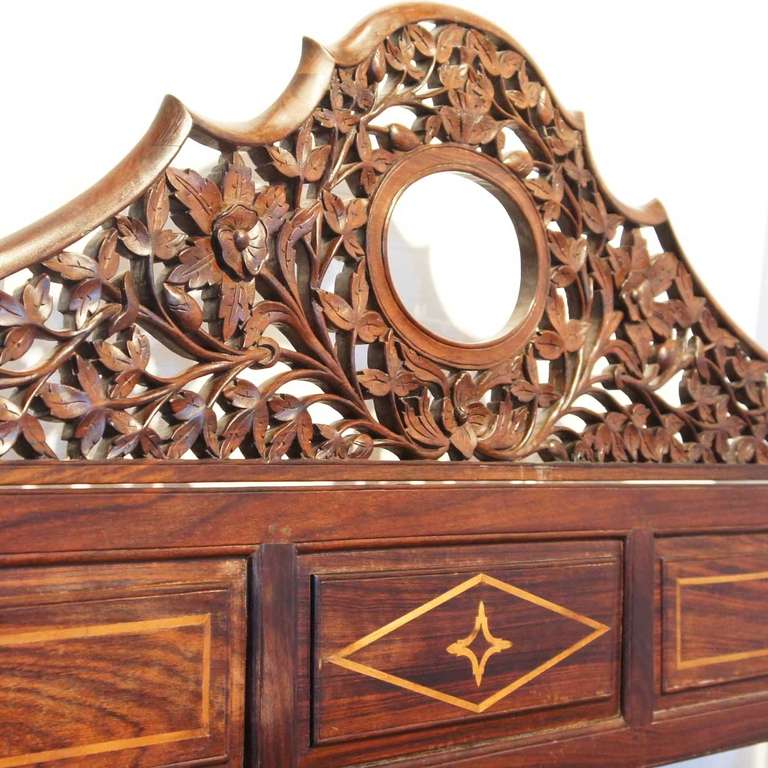 This large, Anglo Indian bed will be magnificent in a large room. It features beautifully carved foliate fretwork on the shaped headboard with an oval opening; above a satinwood inlaid frieze with geometric designs. The four posts raise elegantly,