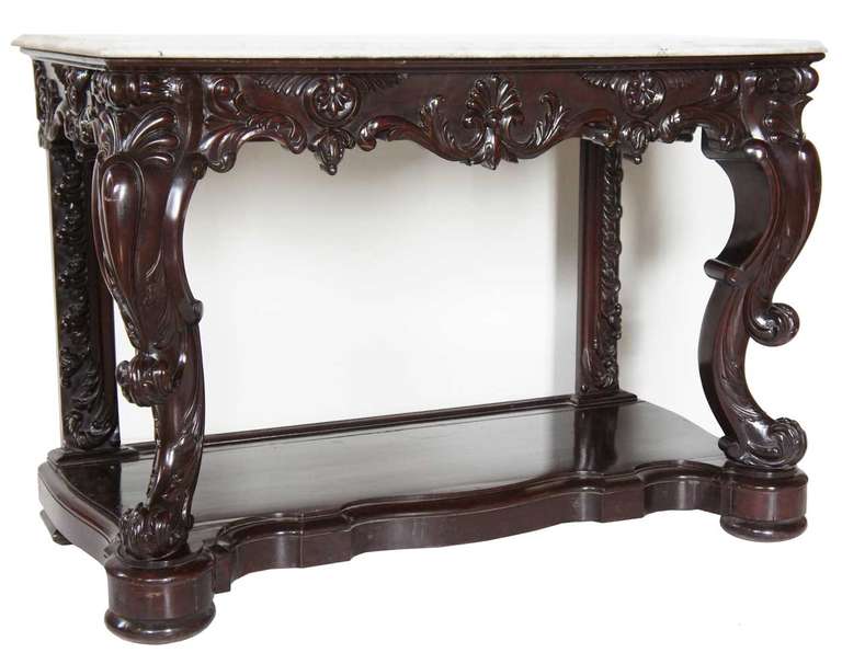 This dramatic table was robustly hand carved with fanciful, scroll, foliate and shell details throughout, including on the straight rear supports. The apron displays floral and shell designs and the stout, somewhat cabriole legs, heavy scrolling,