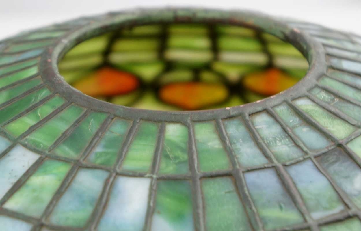 Tiffany Studios (New York, NY, 1878-1933).
This is the most popular form of Tiffany lamp shades as it fits with all patina desk sets, as well as any medium size table base. It is decorated with leaded, opalescent green, white and red glass. Stamped