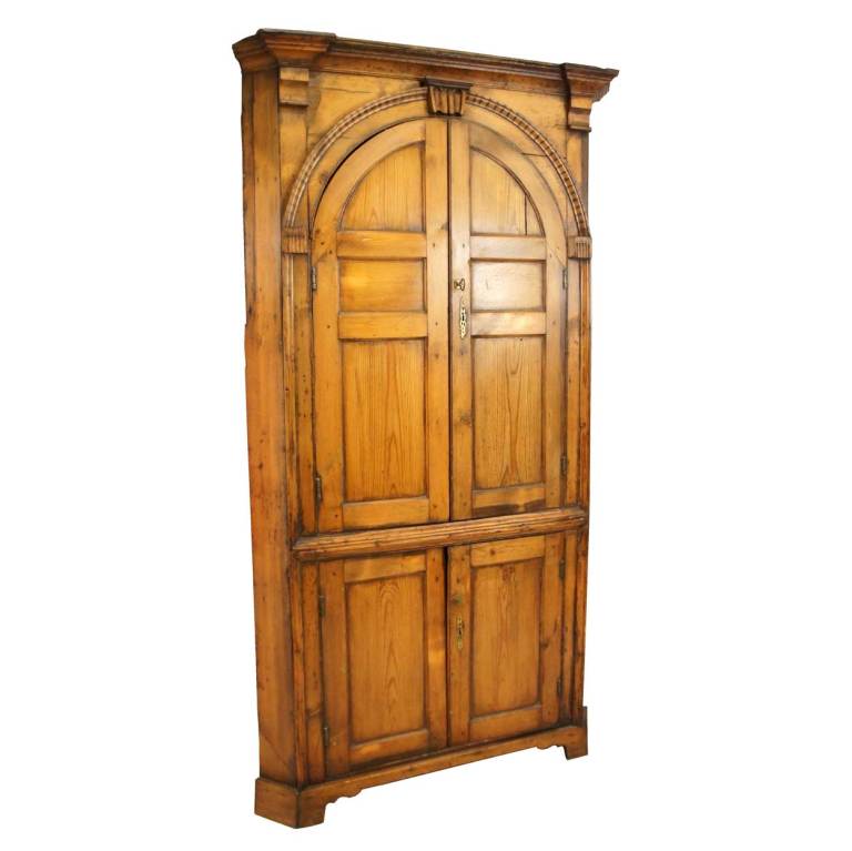 This shallow, canted corner cabinet has a breakfront, molded cornice above arched, double doors with triple fielded panels topped by arched, dentil molding on the case. The base has double fielded panel doors, all raised on bracket feet. The