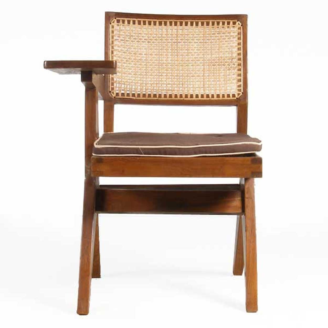 (Swiss, 1896-1967).
This Mid-Century Modern chair has a solid teak frame, with a low, caned backrest and seat, a tablet desk arm and is raised on scissor legs with a double stretcher.

Biography:
Architect and furniture designer Pierre Jeanneret