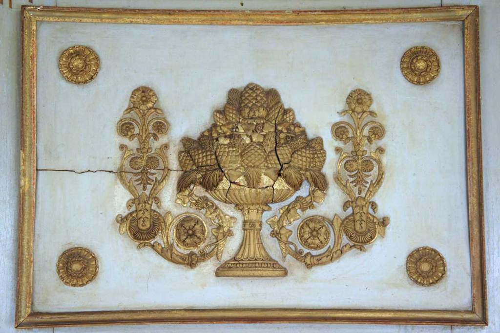 Originally part of a boiserie (room paneling) design, the top panel is carved with a footed, basket replete with pine cones and issuing vines of flowering arabesques. The crest is framed with a rectangular, gilt moulding with rosettes in each