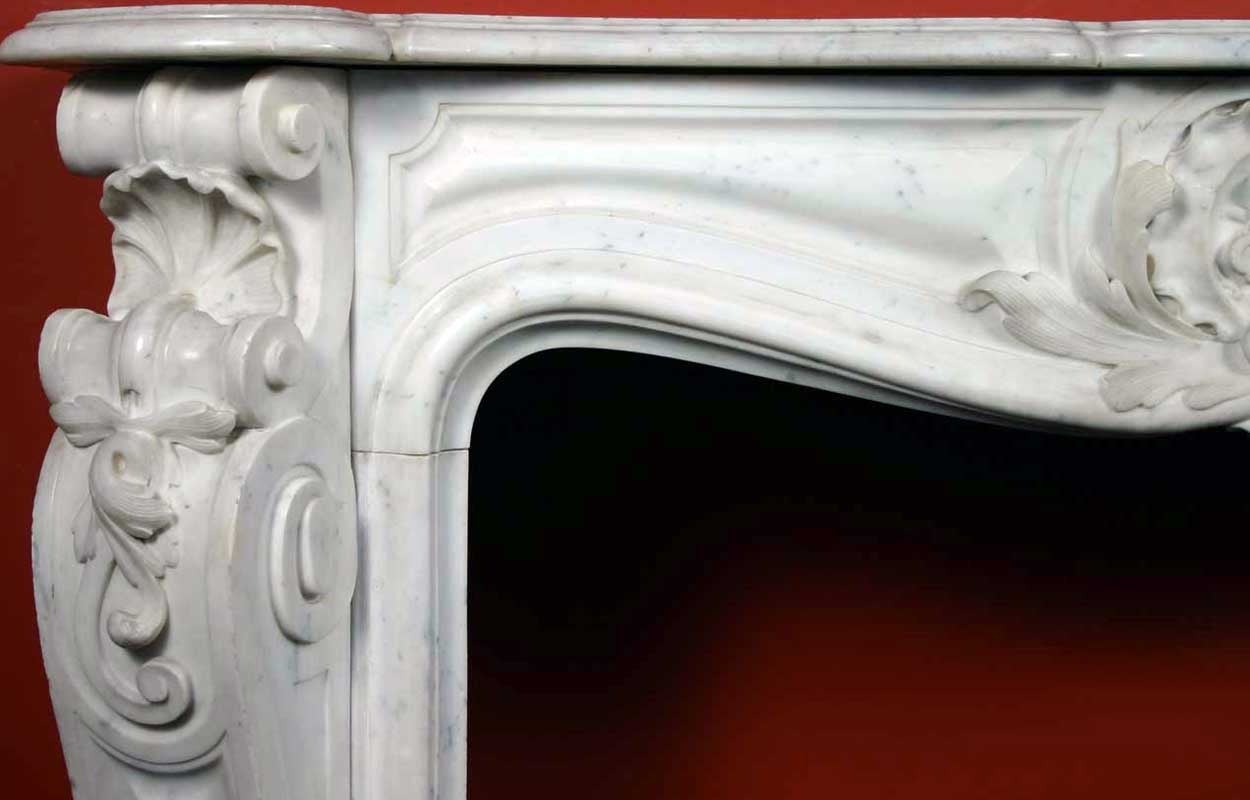 Expertly hand carved, this beautiful chimney features the rococo style of 18th century France. A curved mantel surmounts a stunning frieze featuring an elaborate shell within foliate scrolls. The jambs display full-length S-scrolls, canted on the