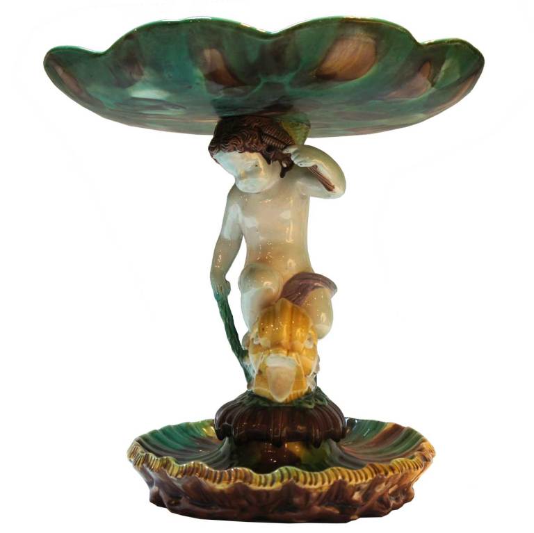 Attributed to Thomas Forester & Sons (Longton, Staffordshire, 1883-1959)  

With a water lily dish supported on a figural stem of a putti riding a dolphin on a dished, scalloped base. The compote is glazed in green, brown, cream and yellow.