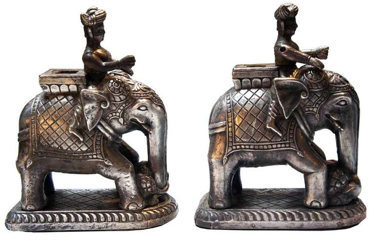This small, but heavy, teakwood pair depicts working elephants moving large objects with their trunks; their handlers astride at the necks. Each is decked out with decorative draping and carries a howdah. There are holes in the tops of the howdah.