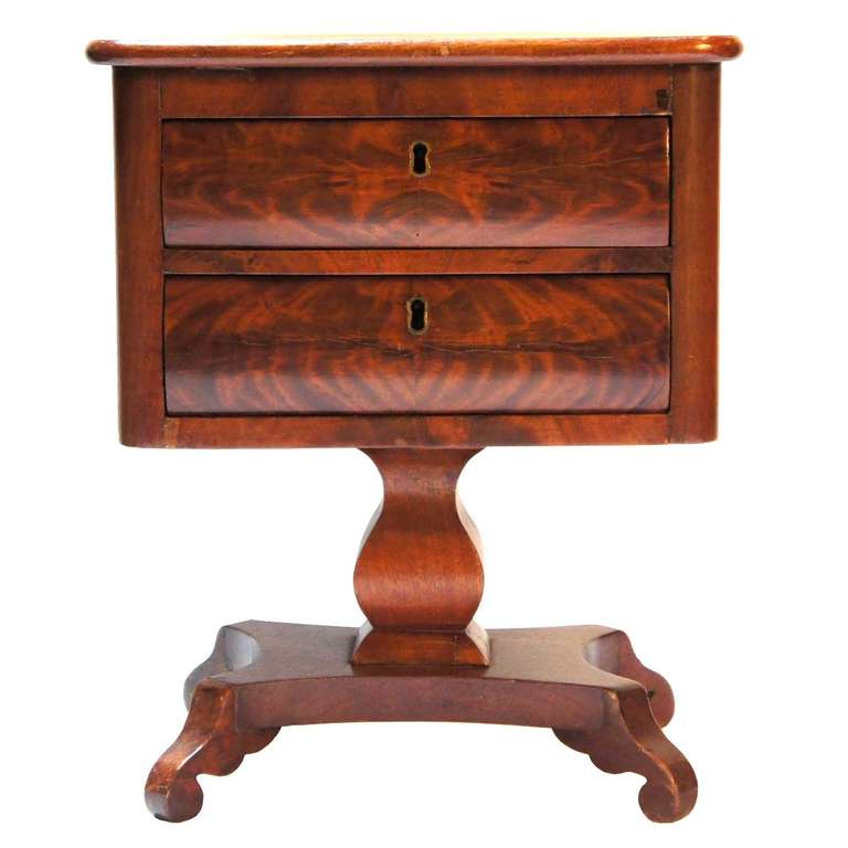 This salesman's sample is designed with two drawers, each having convex fronts, a squared, urn pedestal and a flat base terminating on scrolled feet. Note the especially nice quality of the mahogany veneer. The original key is