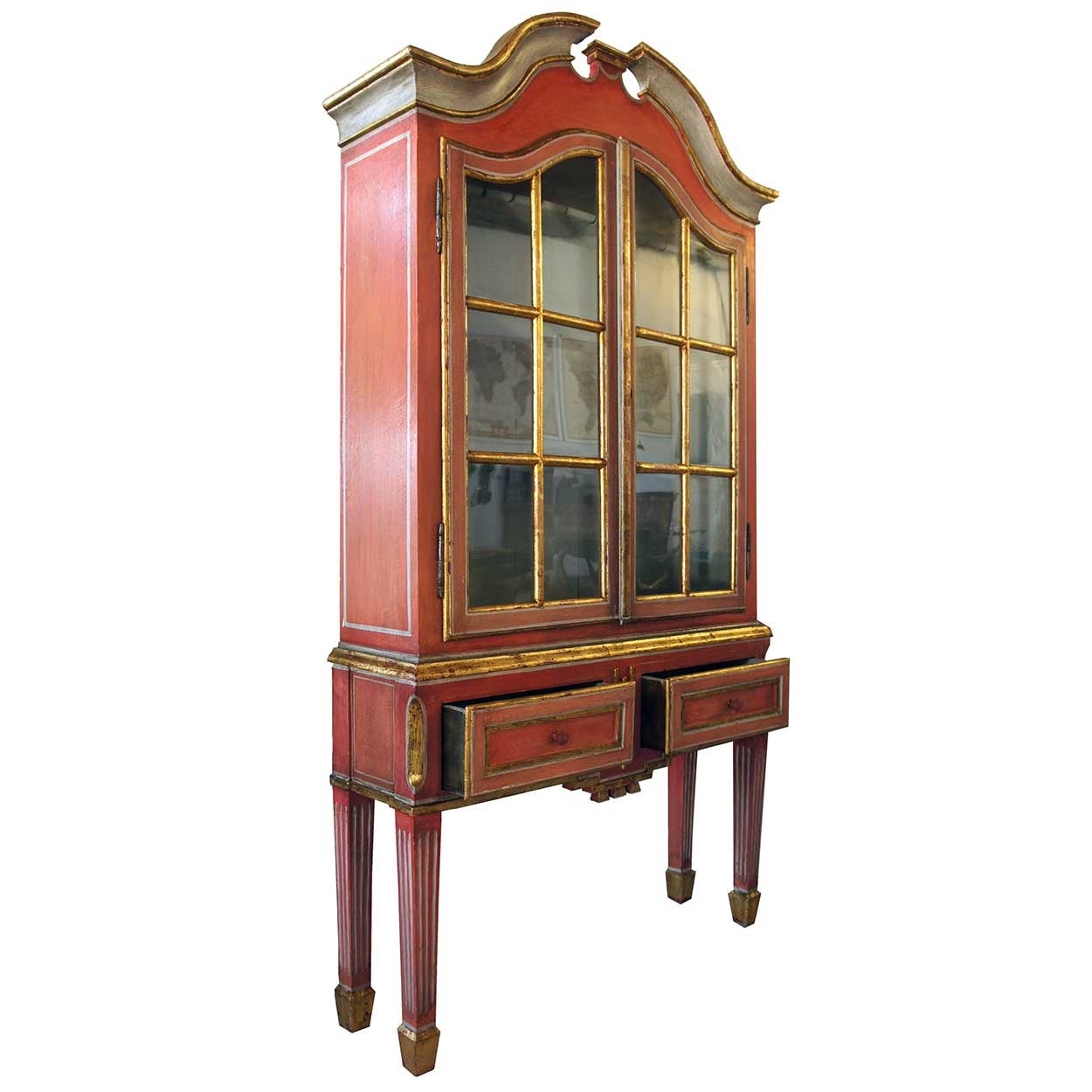 This small and elegant piece was fashioned with a broken pediment top over double, glazed doors that reveal the treasures inside. It sits atop a stand that has two drawers and terminates on tapered, fluted legs. It retains most of the original gilt