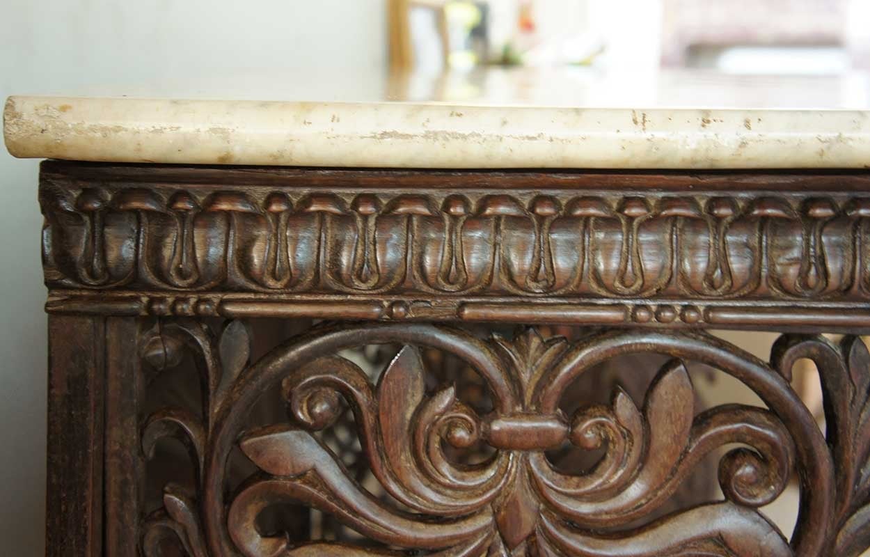 An English colonial console table of Bombay rosewood, hand carved with ornate floral motifs, peacock figures, a carved replica of a shirred fabric back on the base and incredibly detailed lion's paw feet. This species of rosewood, called palisander