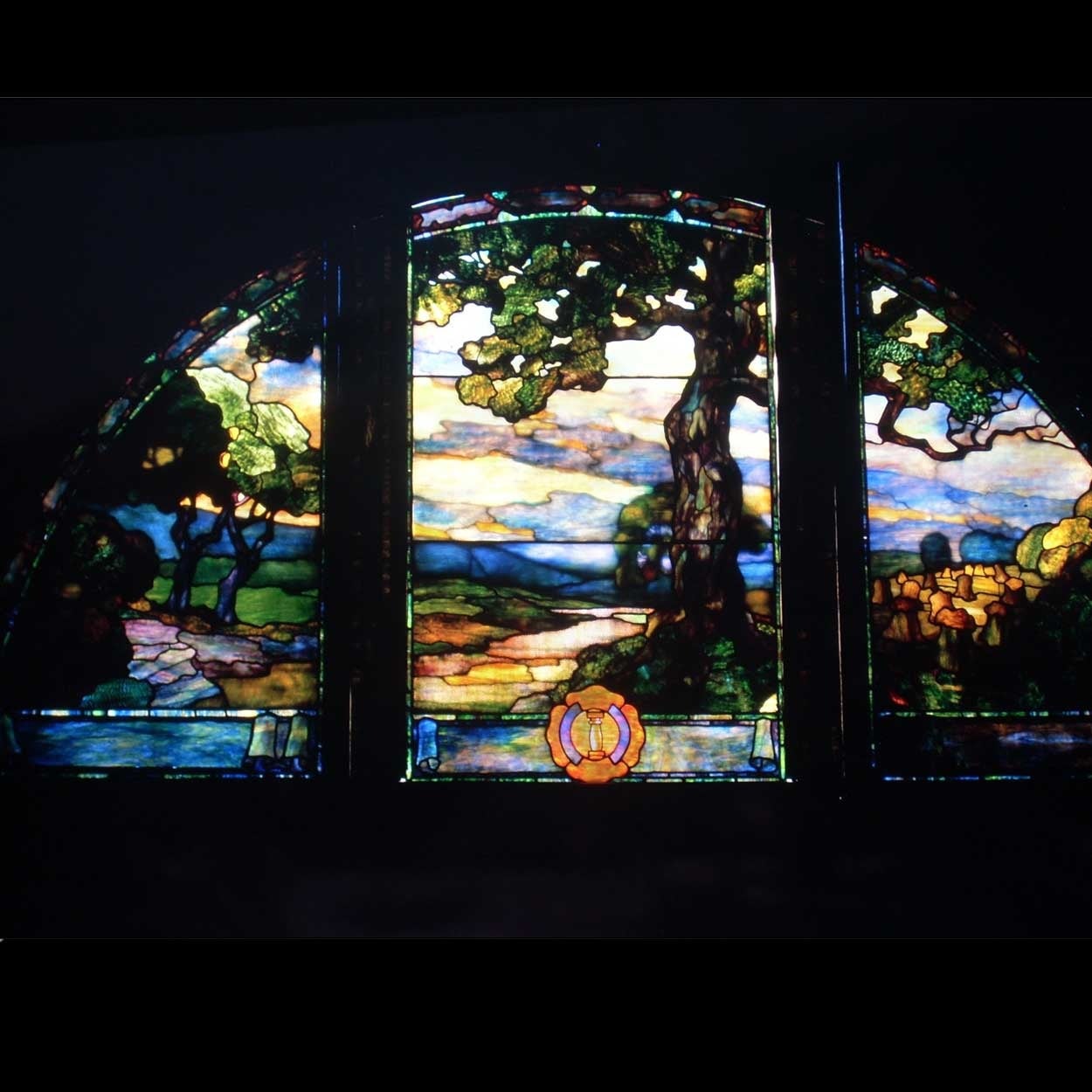 Attributed to Duffner and Kimberly (New York, 1905-11)
An antique, three-part framed arched glass window with leaded, stained and opalescent glass. It features a gnarled, old oak tree with a sunset background representing both knowledge and the end