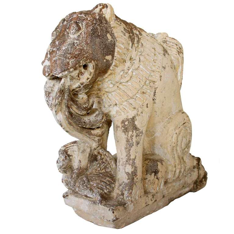 This fierce, but somewhat amusing creature, known as a vyala in northern India, is depicted in the traditional manner with a leonine body and dog head. It was nicely rendered with a chain around his neck and a dramatic, swept up tail. Of mottled