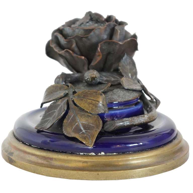 This round inkwell is crafted with blue glaze porcelain with bronze mounts on the base and lid. It is cast with a naturalistic rose stem with a honey bee that forms the lid finial.