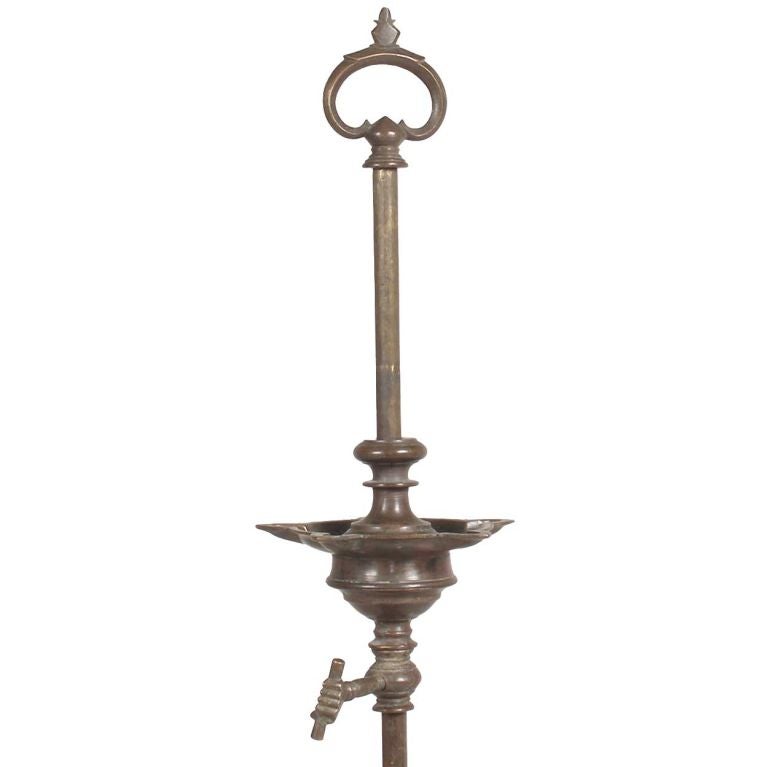 Fashioned after Scottish crusies, this piece was crafted with four wick holders on the oil well, that is surmounted by a pierced handle. The height adjuster has a handle in the form of a human hand and the bottom of the column features wonderful,