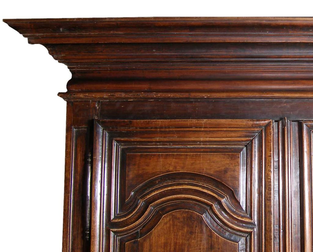 The early wardrobe was handcrafted with a large projecting, stepped cornice above double, paneled cupboard doors with deep relief moldings mounted with original, cut steel escutcheons. The base houses a long drawer with iron ring pulls and