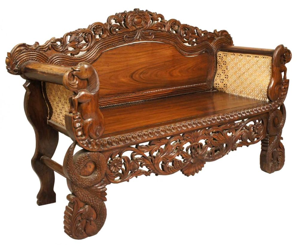 A Burmese interpretation of the Victorian settee, this piece is ornately hand carved, and the seat displays an elaborate, pierced crest rail in an involved, foliate pattern, accented with gadroon borders. The rolled arms are faced with horse