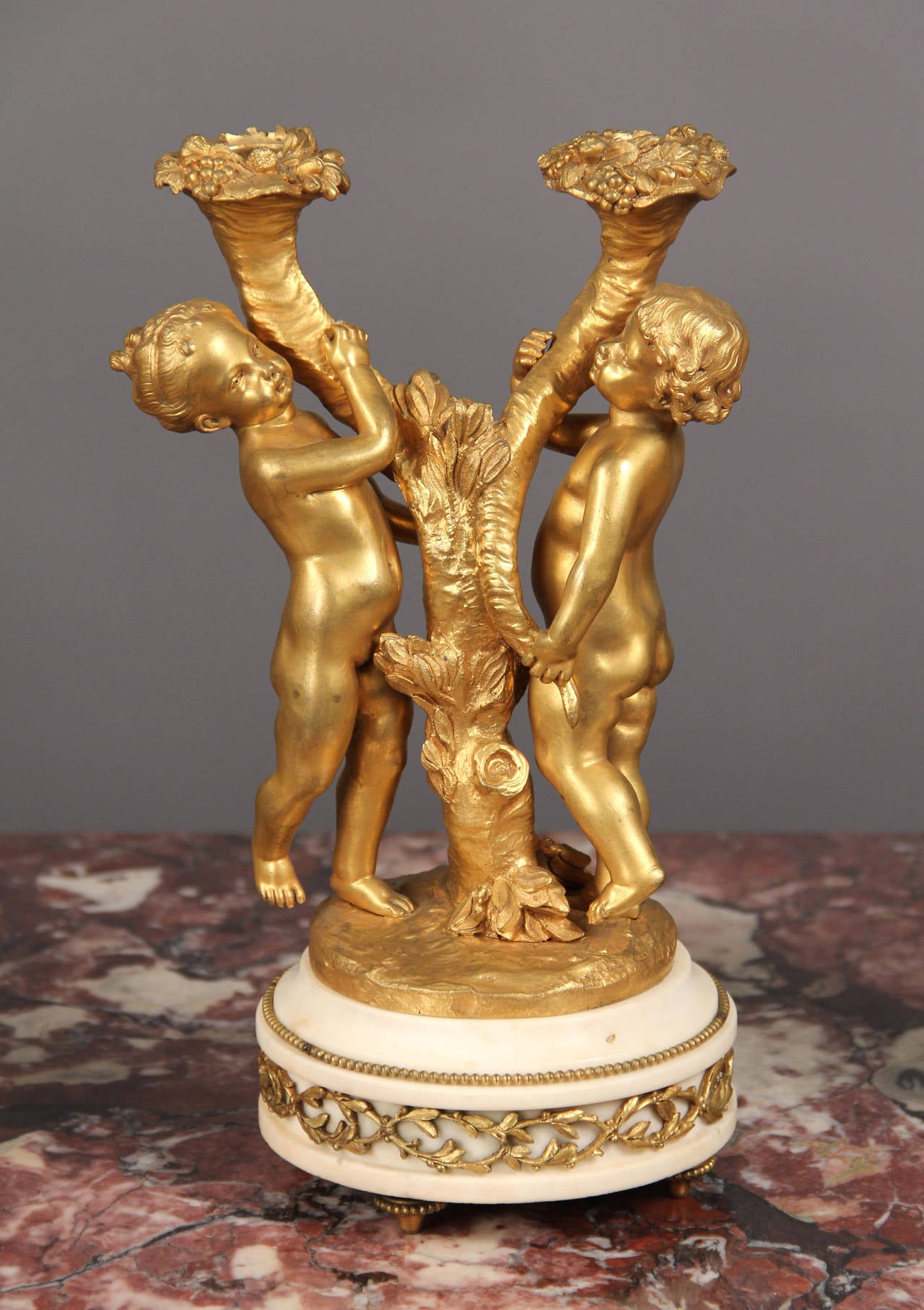 A fine set of four late 19th century gilt bronze and marble two-light candelabra.

Each cast with two cherubs holding candel arm on a bronze-mounted marble base.