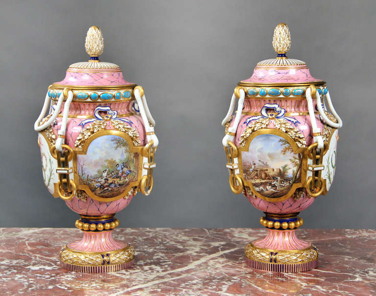 A pair of finely painted late 19th century pink Sèvres style porcelain vases and covers.

Signed Eug Poitevin.

Each with painted designs on all four sides. The front with landscape battle scenes, arms and trophies on the back, and the sides