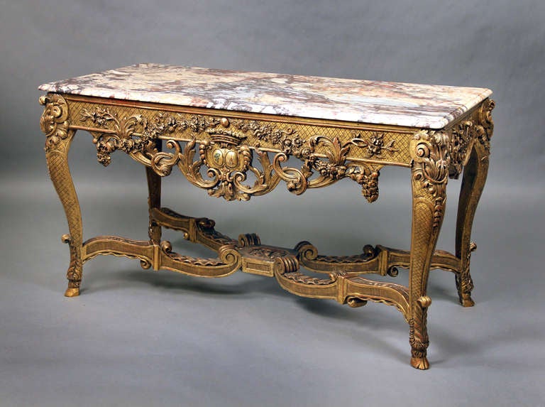 A very finely carved late 19th century Regence style giltwood console.

The shaped rectangular brèche marble-top above a latticework frieze and pierced foliate apron centred by a coat-of-arms, on acanthus-carved cabriole legs joined by a wavy