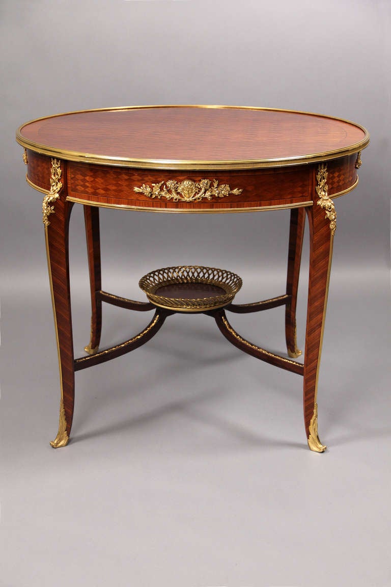 A fine late 19th century Louis XV style gilt bronze-mounted parquetry center table. 

The circular parquetry top of diapered trellis with gilt bronze edging above a similar frieze with finely cast gilt bronze mounts of female masks framed by