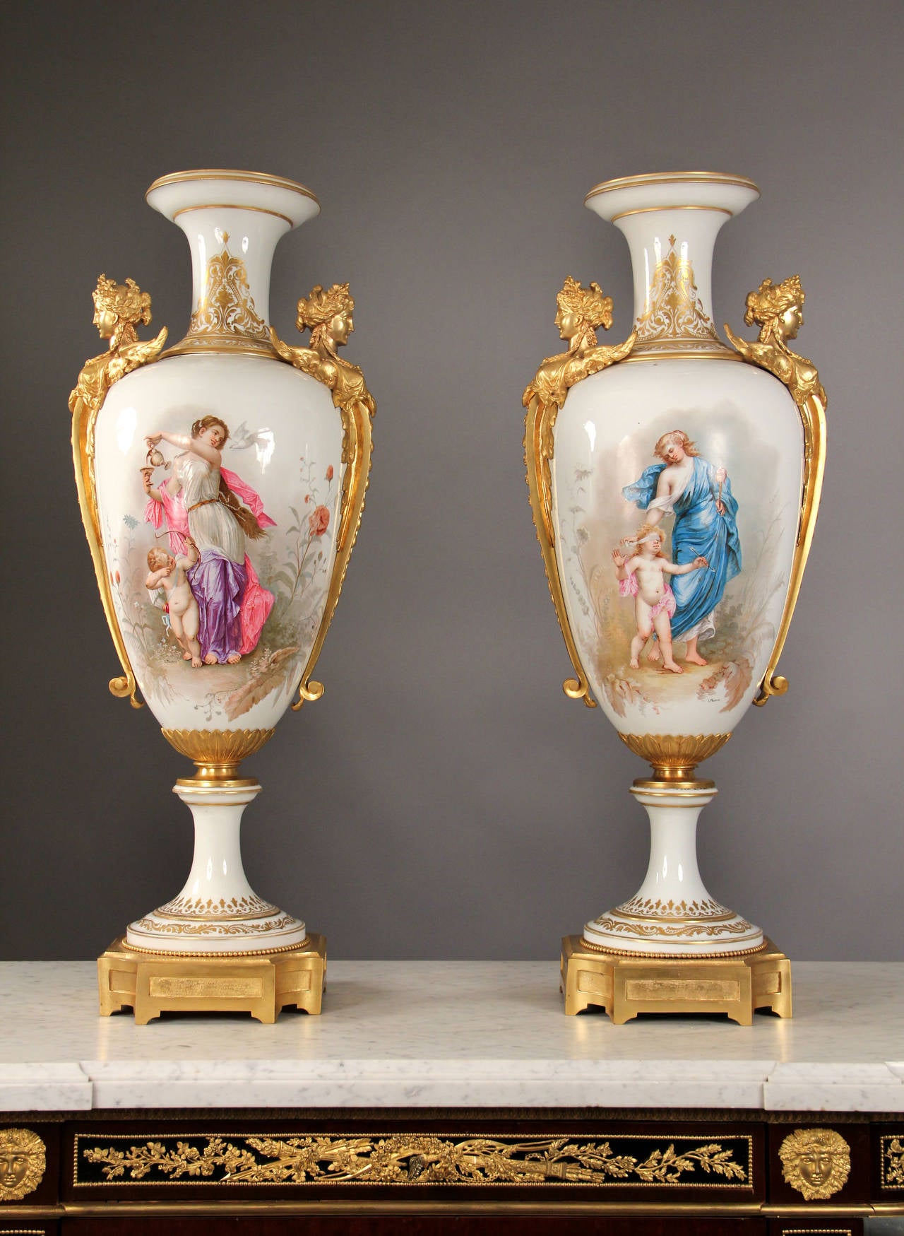 A Very Rare Pair of Late 19th Century Gilt Bronze Mounted White Sèvres Style Vase

Signed L. Malpass.

Each of baluster form, one with a scene of a maiden pouring wine, with cupid on one side and a dove on the other, the second vase with a scene of