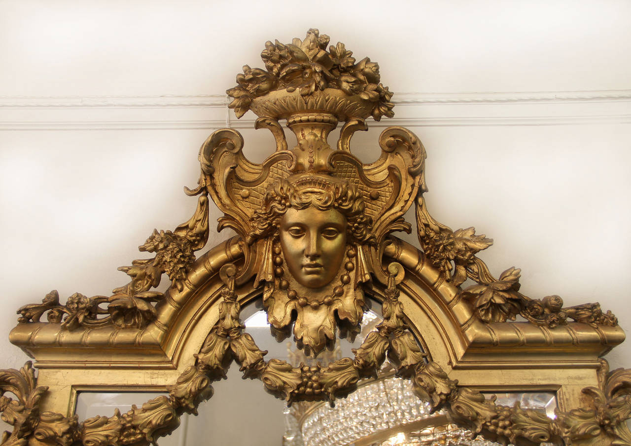 A wonderful and very fine pair of large late 19th century hand-carved giltwood mirrors.

The mirrors of rectangular form. The top centered with a beautiful female mask of the Greek Goddess Aphrodite wearing a crown and beads, surrounded by