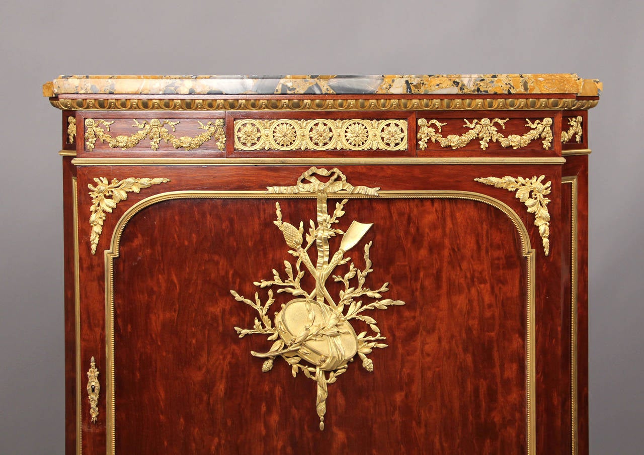 A late 19th century Louis XVI style gilt bronze-mounted mahogany cabinet

by François Linke.

Surmounted with a marble top, above a frieze and a bronze-mounted upper cupboard door, the bottom with tambour doors.

Pictured on Page 277