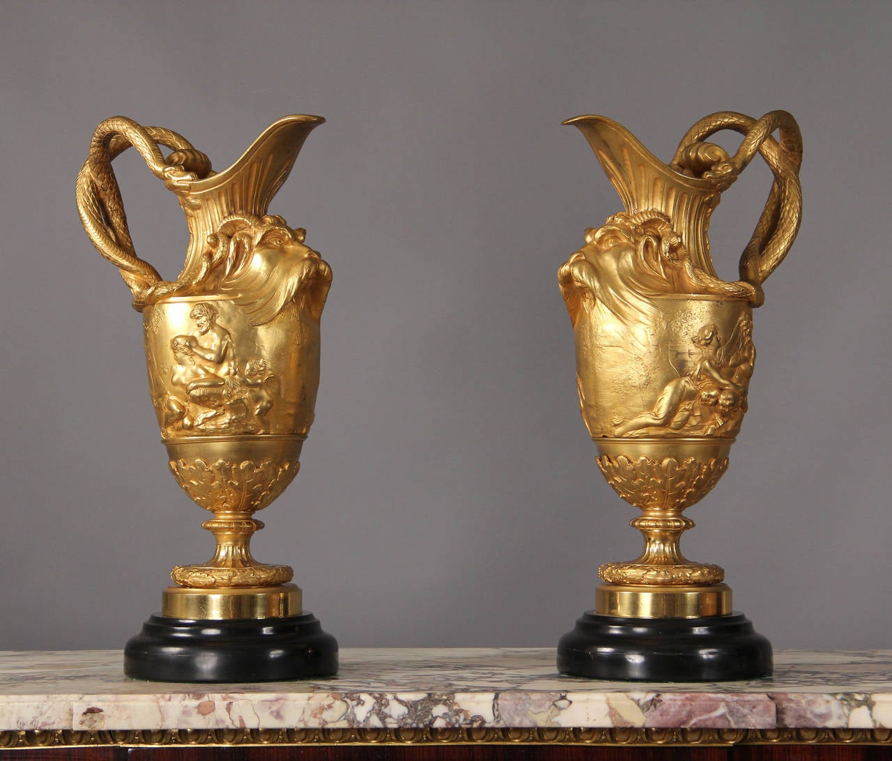 Late 19th century gilt bronze three-piece garniture.

After Claude Michel Clodion.

Consisting of a vase of tapering form applied with two grotesque masks hung with laurel garlands above a frieze cast in relief with depictions of putti pulling
