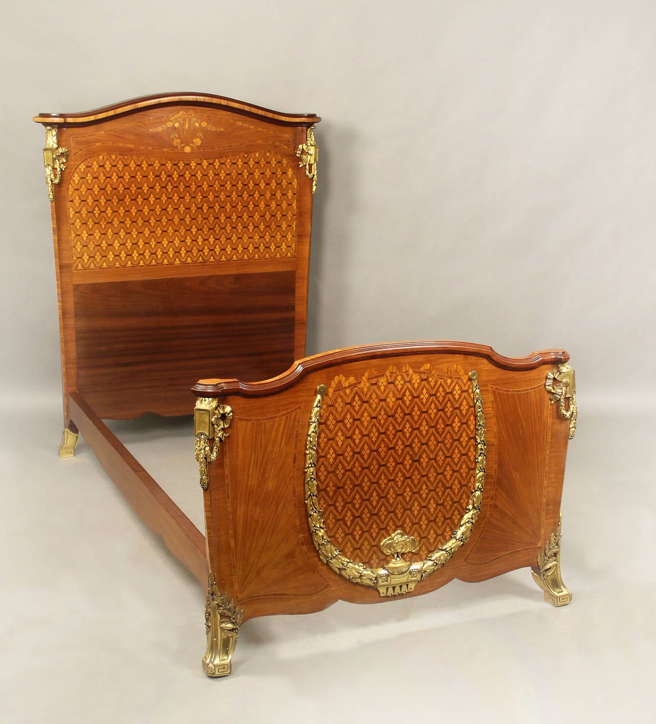 A Beautiful pair of late 19th century Transitional style gilt bronze-mounted inlaid marquetry and parquetry twin size beds.

The head and foot boards with matching side bronze mounts and parquetry designs, top of the head board with inlaid flowers