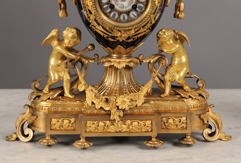 Late 19th Century Gilt Bronze Mounted Three Piece Cobalt Blue Sèvres Style Clock Set

Comprising: a round clock with a final with two birds; a pair of five-light candleabra with scrolled branches issuing from round shaped vases painted with a