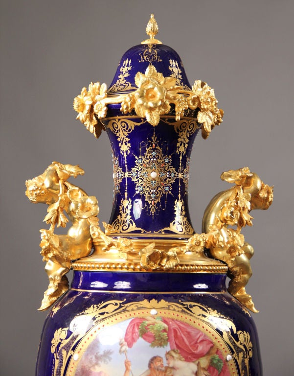 An impressive Sèvres style gilt bronze mounted porcelain vase and cover, the base with an integral clock.

This large and unusual vase has a domed cover with an acorn finial above a trumpet shaped neck with a gilt bronze collar supporting two