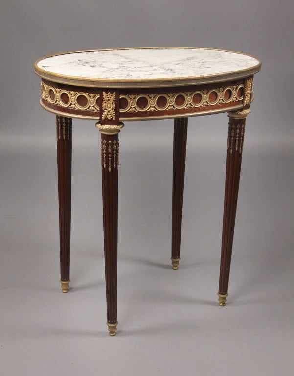 A late 19th century Louis XVI style gilt bronze mounted marble-top lamp table.

A shaped oval marble insert top, above a bronze mounted frieze with a single center drawer.