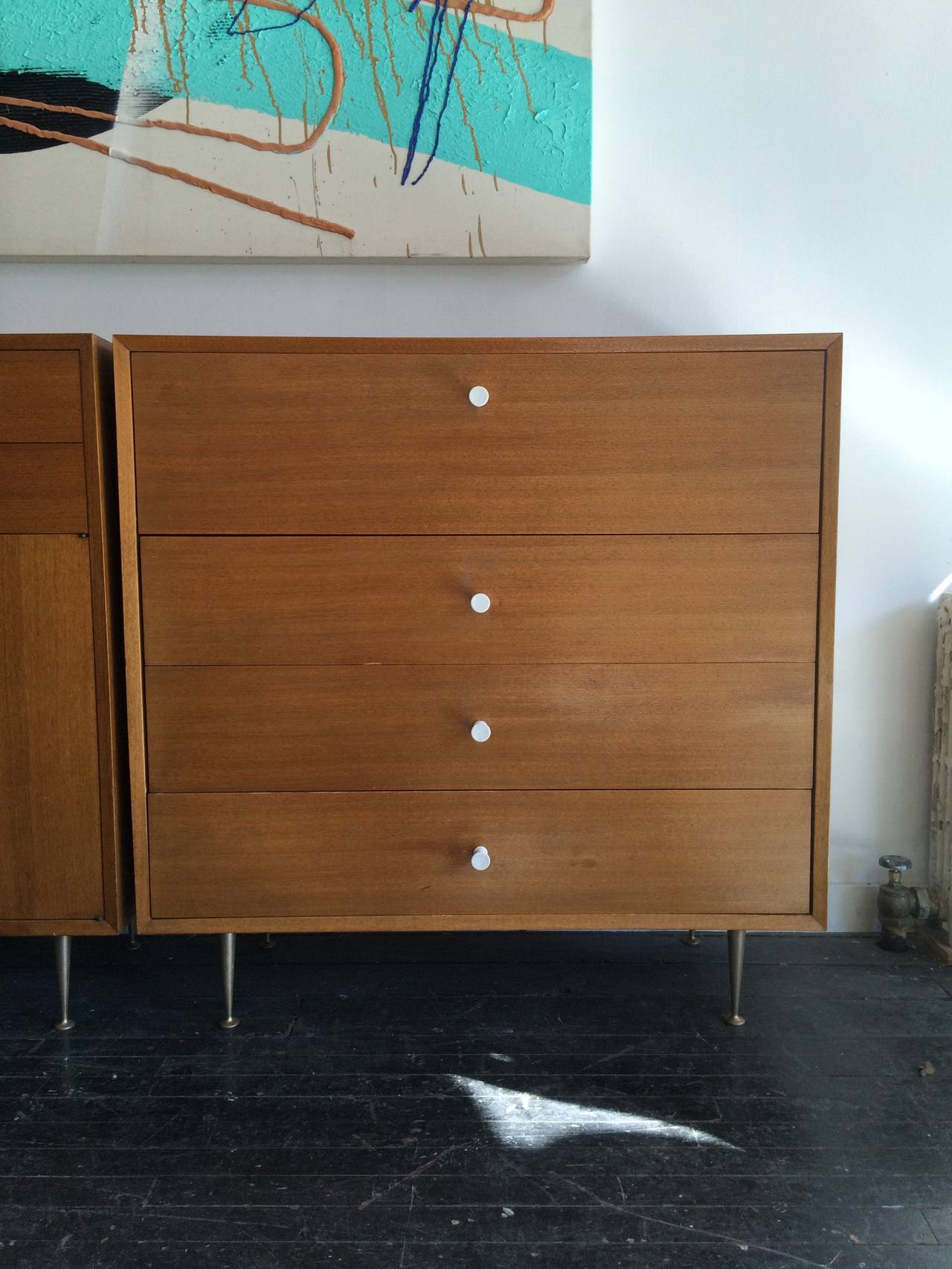 A custom pair of George Nelson basic storage cabinets featuring hardware normally associated with the Thin Edge Group. Designed for Herman Miller, circa 1955. Spun aluminum legs.