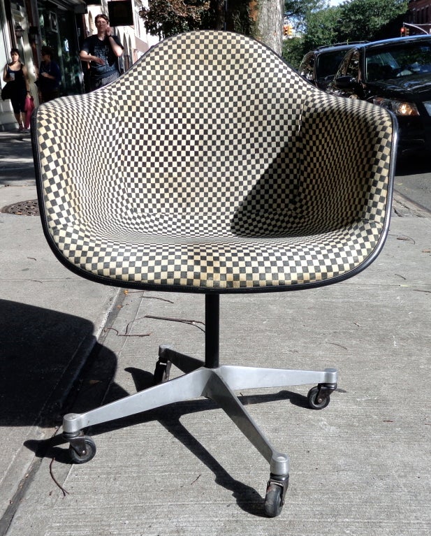 Set of 6 arm and side chairs designed by Charles and Ray Eames for Herman Miller. White shells with original Alexander Girard ivory and black checkered upholstery. On caster bases.