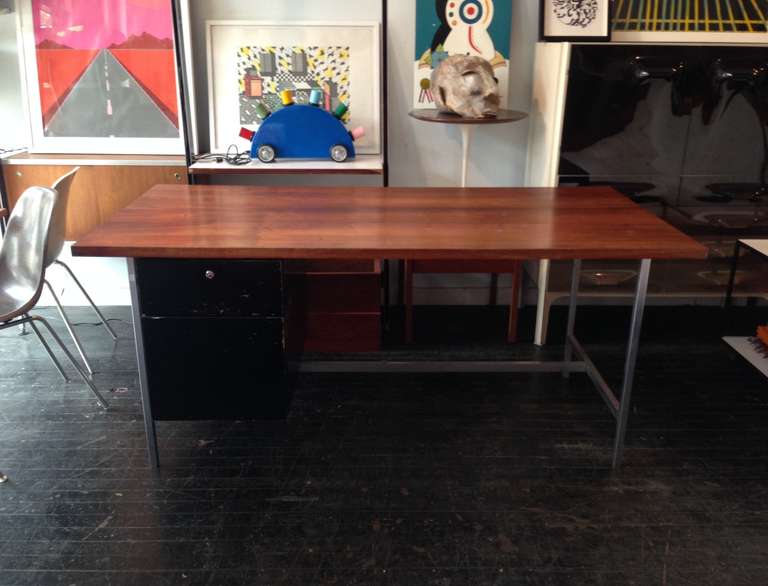 Large executive desk designed by Florence Knoll for Knoll in 1952. Solid walnut top with steel frame. Cabinet with black lacquer drawers.