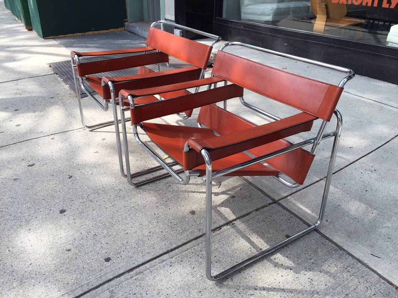 A pair of Wassily lounge chairs designed by Marcel Breuer in 1968. 
Base: Tubular steel, polished chrome finish. Seat, back and arms: Double faced cowhide.