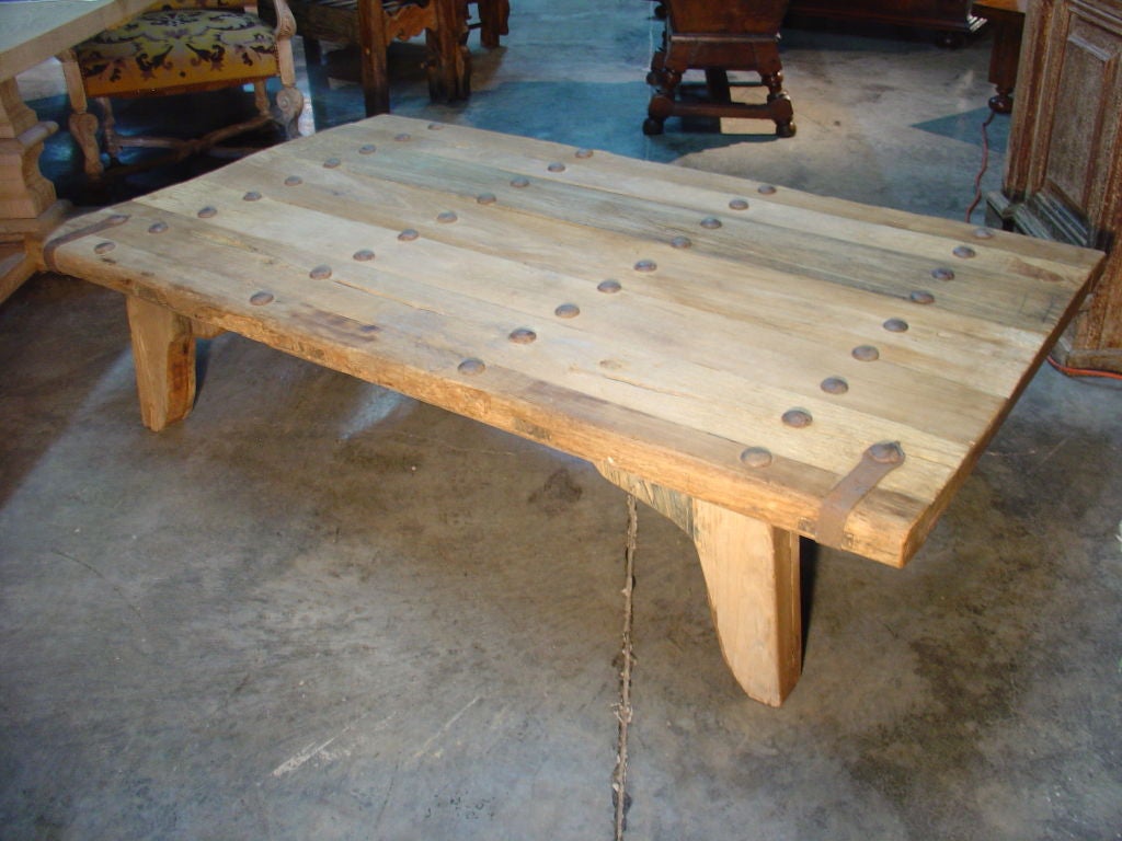 A Late 1800s French Oak Plank Door with Iron Nailheads and Two Iron Straps Repurposed into a Coffee Table; Age;  Legs are antique wood added recently.<br />
<br />
This magnificent thick antique French oak plank door from the 1800's or maybe even