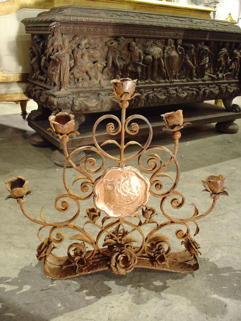 Circa 1850

This beautiful hand forged iron candelabrum with five arms has been ornamented with roses throughout.  The bobeches are individual roses made with wafer thin petals having leaves upholding the roses.  C-and S-scrolls make up the shape