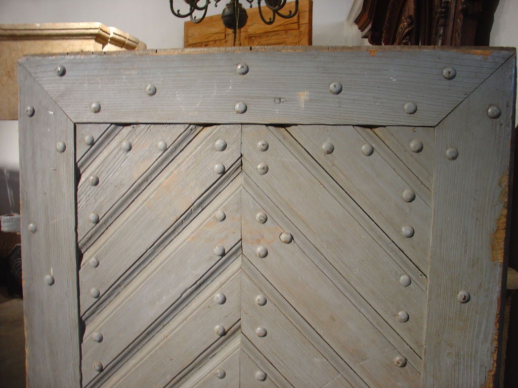 This antique door from Corsica has book matched diagonal boards on its central panel and is framed by vertical and horizontal stiles and rails.  The door has been painted a grey/blue color at some point in its history, so it may be difficult to see