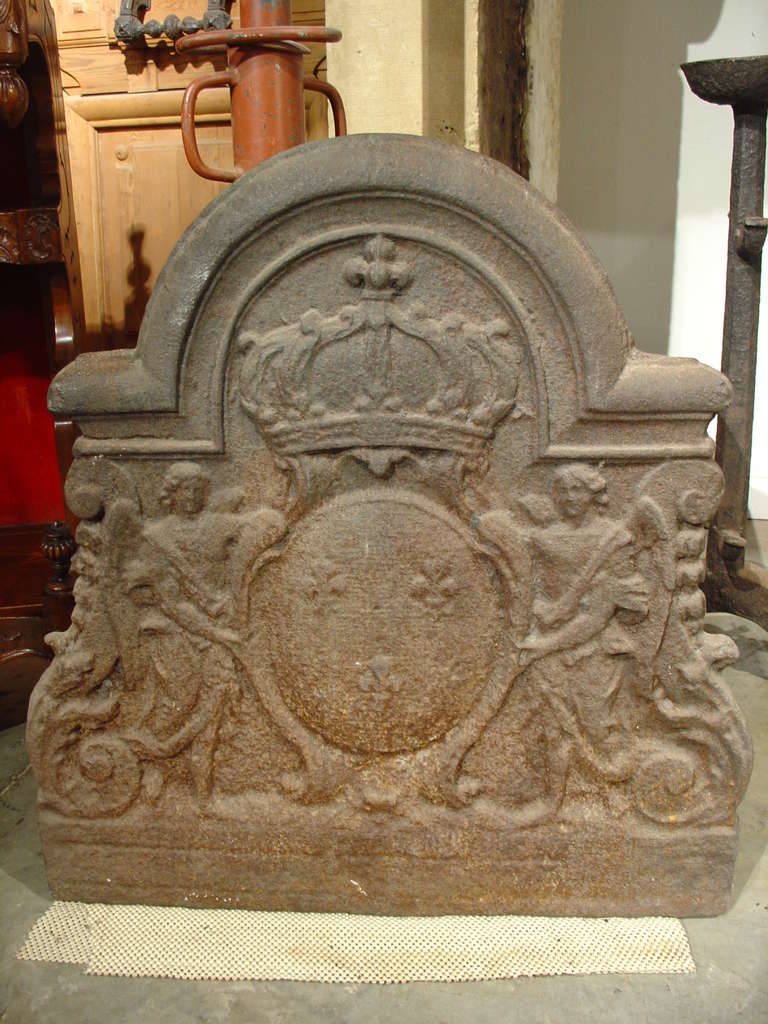 This is an antique French fireback from the 1700’s bearing a Coat of Arms.   It has an unusual architectural of moldings in the shape of a center dome with two right angles on either side. The sides follow the shape of the husks and acanthus leaf