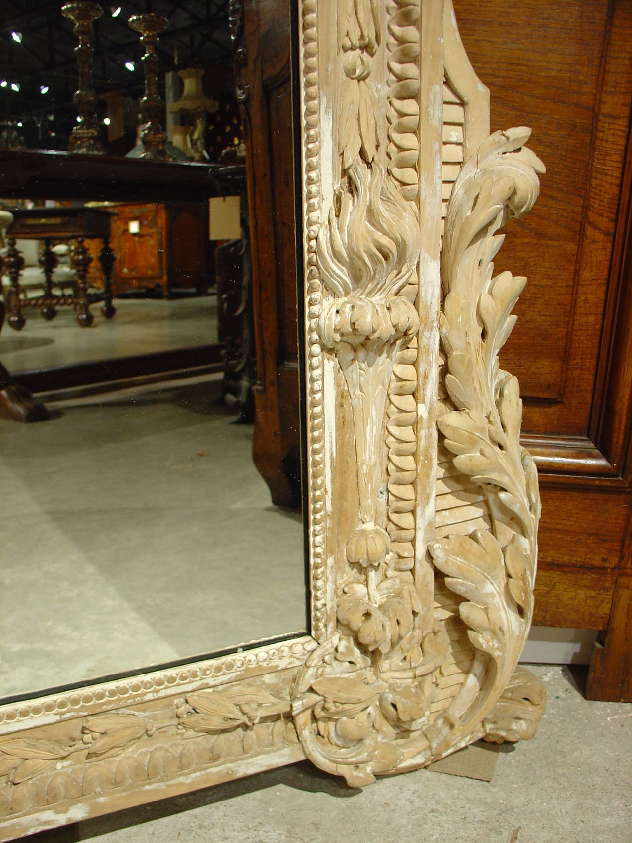 The hand carving on this French mirror is absolutely stunning. From the tiniest flower to the large relief of the flowers in the garlands, the details and proportions blend beautifully. The old parcel paint finish is typical of years of wear to the