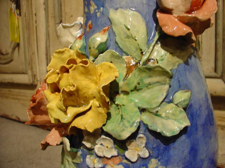 Ce vase barbotine français ancien est orné de quatre tiges foliacées de roses en gros relief de couleurs et de stades de maturité différents. Des fleurs et des feuillages en bas-relief composent le reste de la composition florale:: sur un fond de