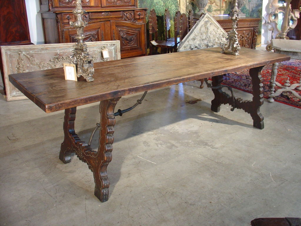 This antique Catalan style rectangular table from Spain has hand forged scrolling iron stretchers and shaped end supports.  The top’s edges have incised star motifs and the shaped end supports have incised lines echoing the shapes.  We have chosen