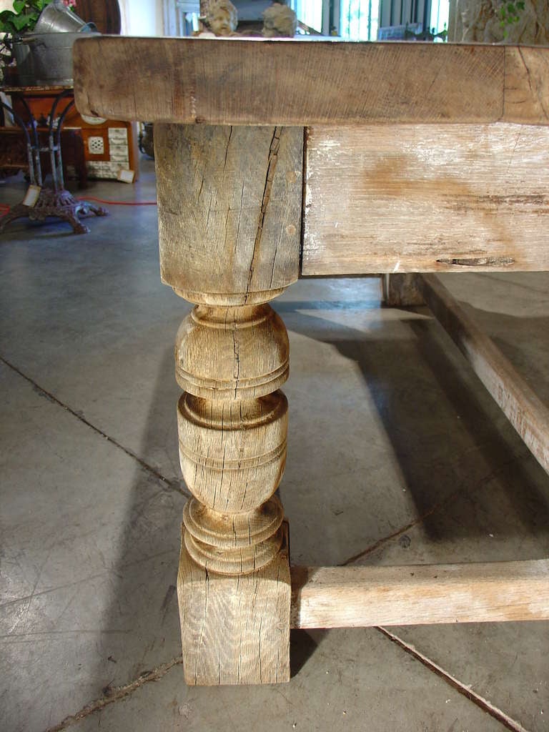 This wonderful antique French table in the Renaissance style has been stripped and partially whitewashed.  It has motifs on the apron of scrolling rinceau over baluster legs on four block feet.  The stretchers connect the four block feet. Versatile