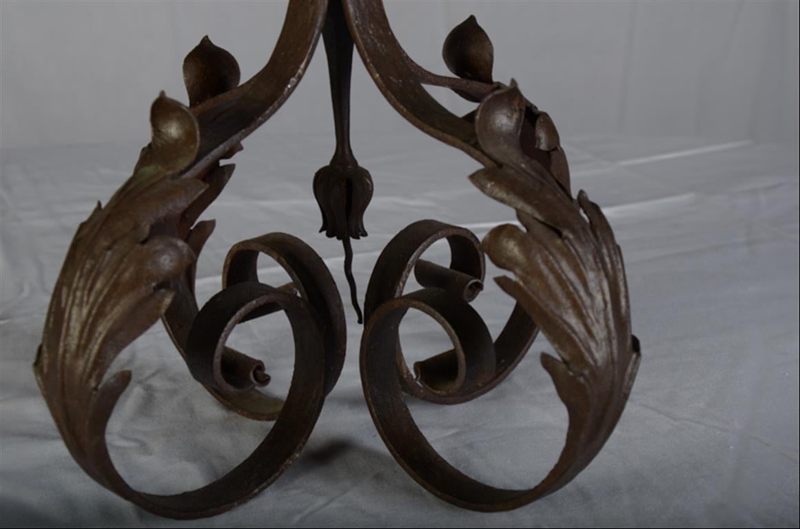 Hand forged in France around 1900, this graceful pair of candelabras has subtle s-curved acanthus leaf stems for the lights or candles.  The central light is a series of stems in an oval with triple headed buds or stylized fleur de lys beneath the