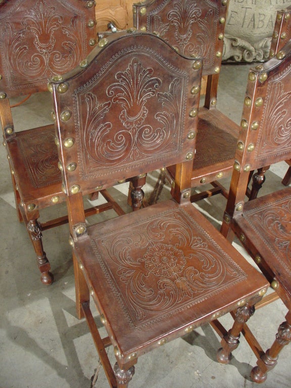 These wonderful antique Portuguese style chairs from the early 1900's, have beautifully embossed leather backs and seats affixed to the wood with medium sized brass nailheads.  The backs have an embossed motif of a stylized central palmette rising