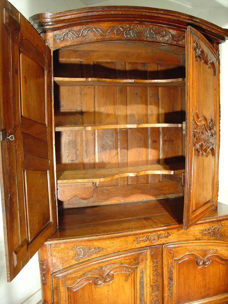 This is a rare period Regence French Buffet a Deux Corps from the Auvergne region of France.  It has a deep, rich patina along with deep carvings and motifs with worn reliefs, showing its 300 year old age. On the door panels, notice how the